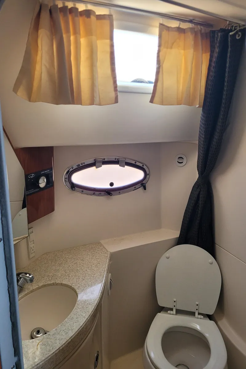Slide: The Image of 2006 Regal 3060 Window Express boat bathroom with sink, toilet, and porthole window. - 21