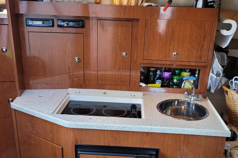 Slide: The Image of 2006 Regal 3060 Window Express boat kitchen with stove, sink, and wooden cabinetry. - 34