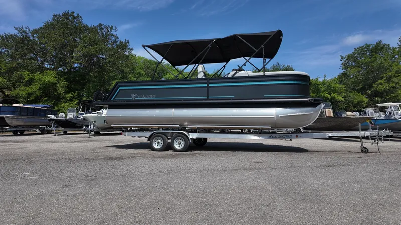 Slide: The Image of 2025 Viaggio Z22S pontoon boat on trailer, parked outdoors under clear blue sky. - 12