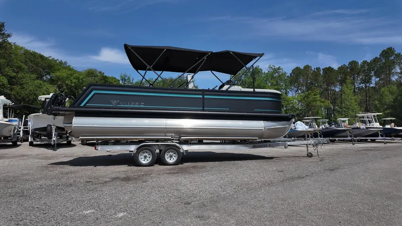 Slide: The Image of 2025 Viaggio Z22S pontoon boat on trailer, parked outdoors with trees in background. - 16
