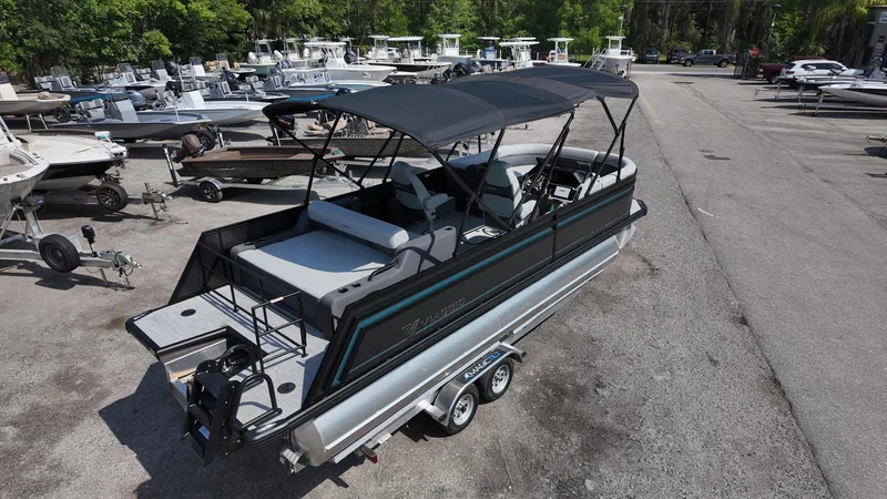 Slide: The Image of 2025 Viaggio Z22S pontoon boat with canopy, parked on a trailer in a marina. - 25
