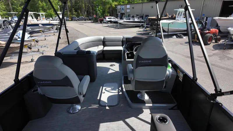 Slide: The Image of 2025 Viaggio Z22S pontoon boat interior with seating and helm, parked at a marina. - 30