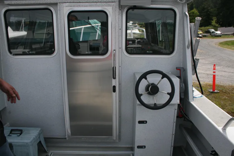 Slide: The Image of 2017 North River 2500 S Sew Hawk OS boat interior with steering wheel and door. - 6