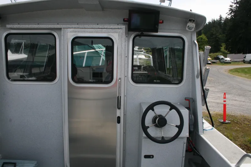 Slide: The Image of 2017 North River 2500 S Sew Hawk OS boat cockpit with steering wheel and windows. - 9
