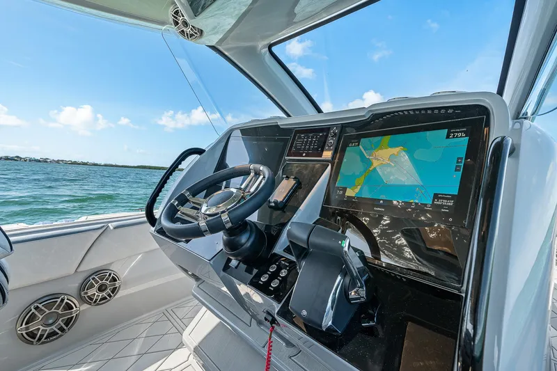 Slide: The Image of 2025 Deep Impact 369 Sport boat dashboard with navigation screen, steering wheel, and ocean view. - 28