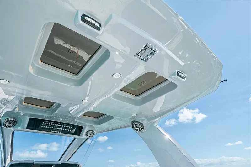 Slide: The Image of 2025 Deep Impact 369 Sport boat roof with skylights and speakers against blue sky. - 48
