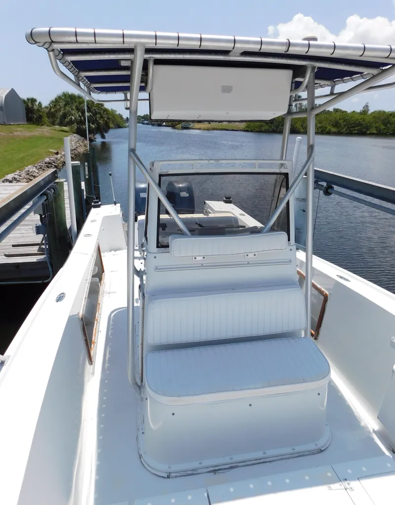 Slide: The Image of 1985 Mako 254 Center Console boat docked by a scenic river. - 16