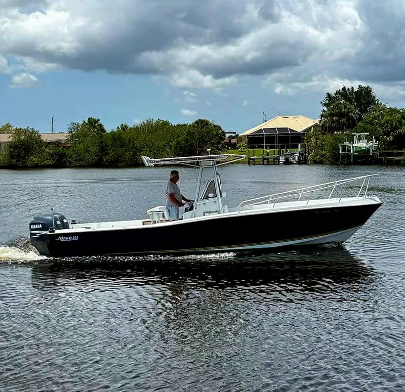 Slide: The Image of 1985 Mako 254 Center Console boat cruising on a calm river under cloudy skies. - 2