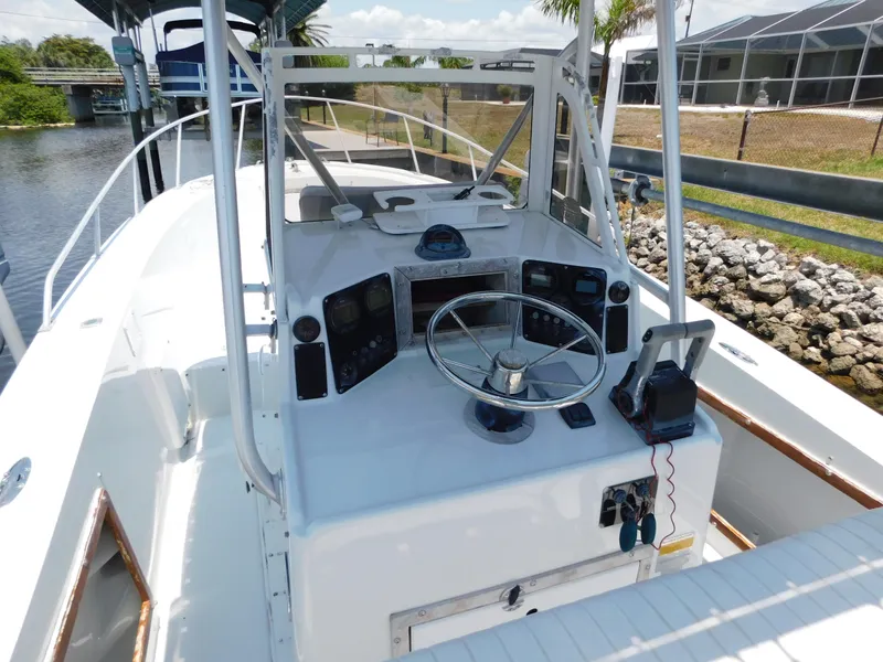 Slide: The Image of 1985 Mako 254 Center Console boat with steering wheel and control panel, docked by a canal. - 8