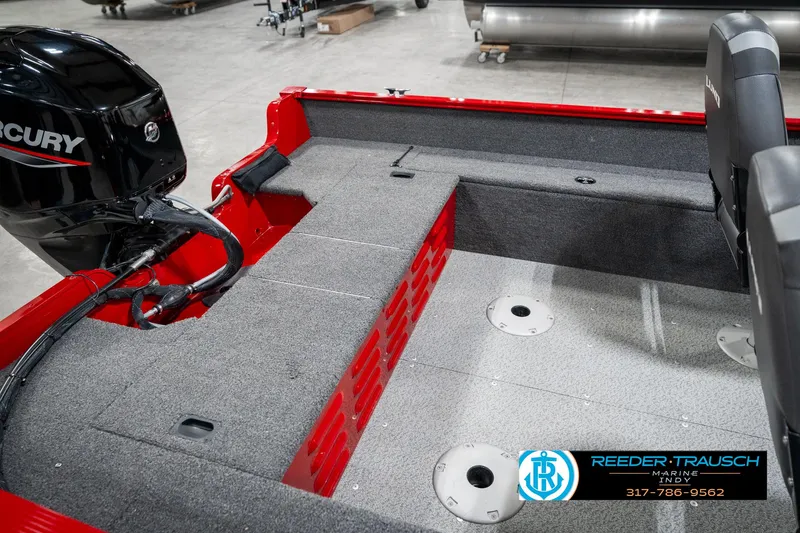 Slide: The Image of 2021 Lund 1650 ANG SS boat interior with Mercury engine, gray carpet, and red accents. - 23