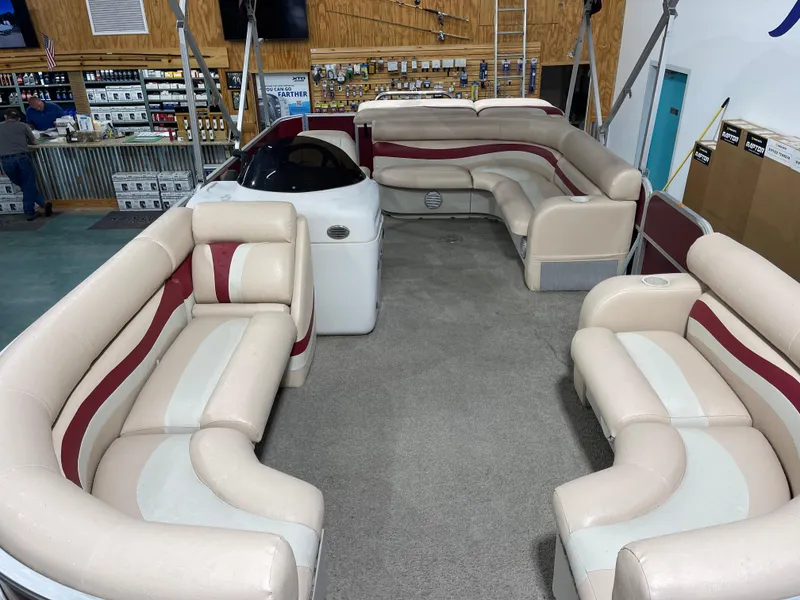 Slide: The Image of 2010 South Bay 520CR pontoon boat interior with beige and red seating in a showroom. - 12