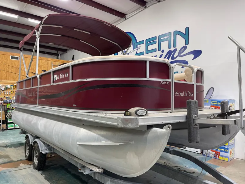 Slide: The Image of 2010 South Bay 520CR pontoon boat in showroom, maroon color, on trailer. - 5