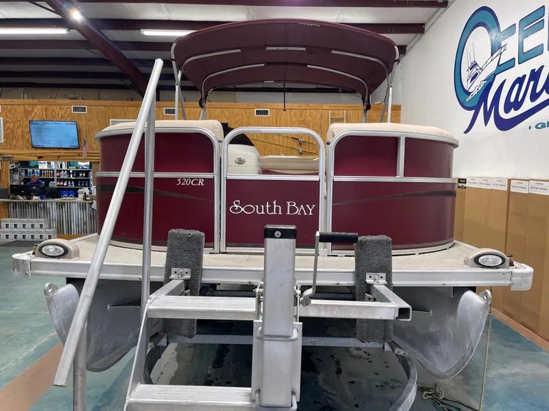 Slide: The Image of 2010 South Bay 520CR pontoon boat displayed indoors at a marine dealership. - 6