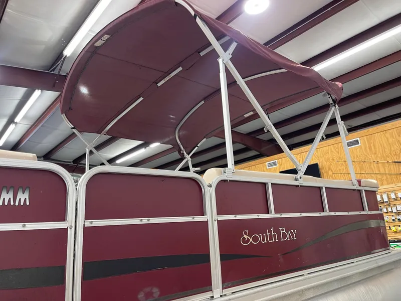 Slide: The Image of 2010 South Bay 520CR pontoon boat with maroon canopy in indoor storage. - 8