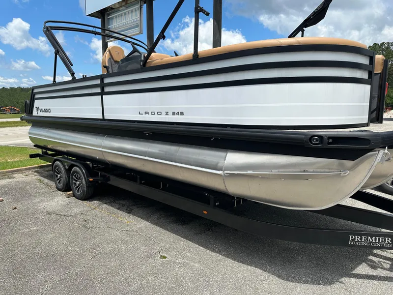 Slide: The Image of 2024 Viaggio Z24S pontoon boat on trailer, parked outdoors under a blue sky. - 1