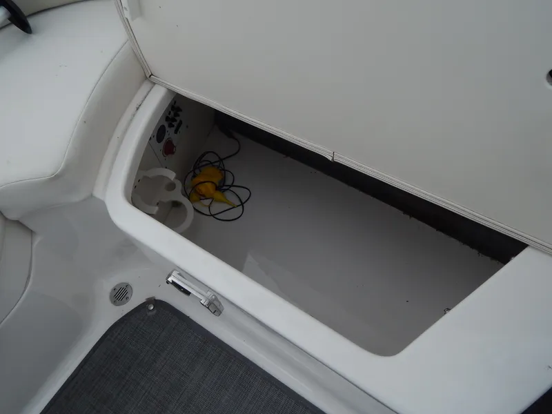 Slide: The Image of 2016 Chaparral 246 SSi boat storage compartment with electrical cables and cup holder. - 30