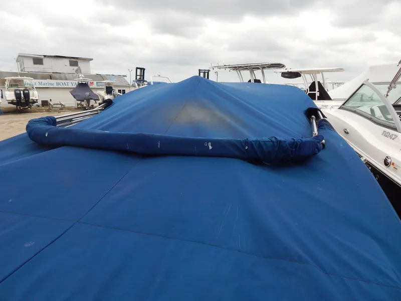 Slide: The Image of Covered 2016 Chaparral 246 SSi boat in storage, blue tarp, cloudy sky. - 47