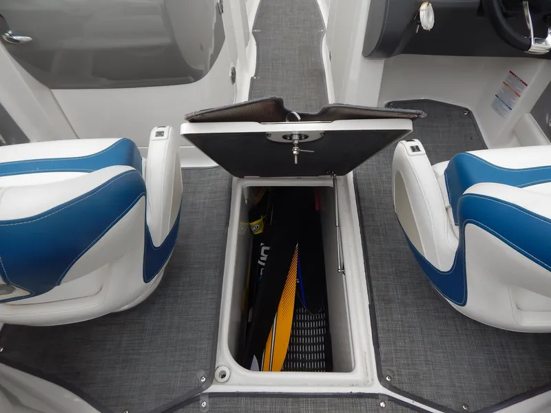 Slide: The Image of 2016 Chaparral 246 SSi boat interior with open storage compartment between blue seats. - 7