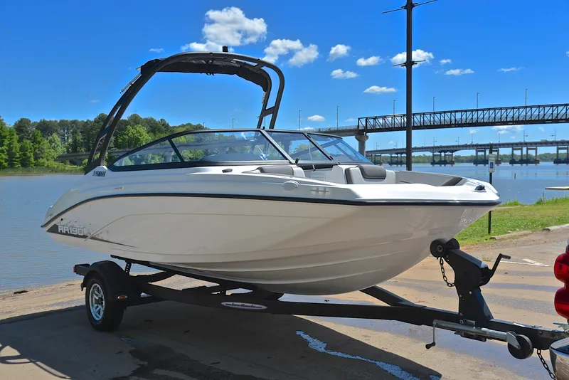 Slide: The Image of 2023 Yamaha Boats AR190 on trailer by a river under a clear blue sky. - 16