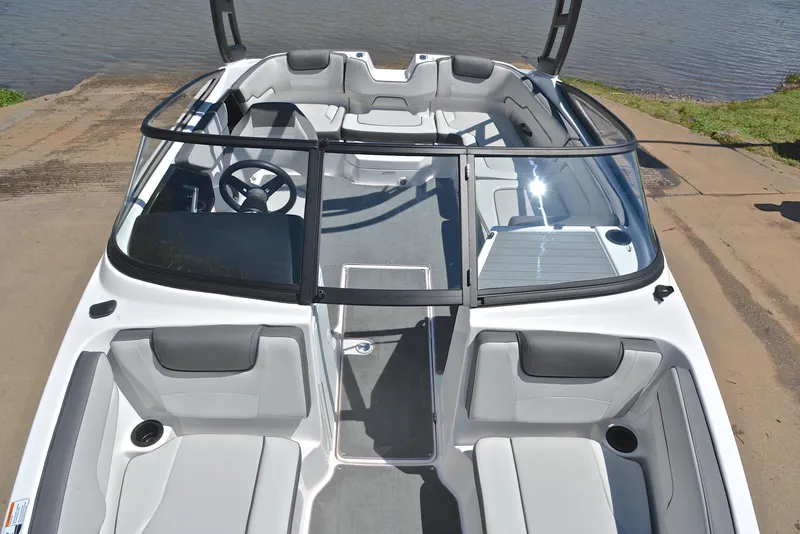 Slide: The Image of 2023 Yamaha Boats AR190 interior with seating and steering, docked by the water. - 20