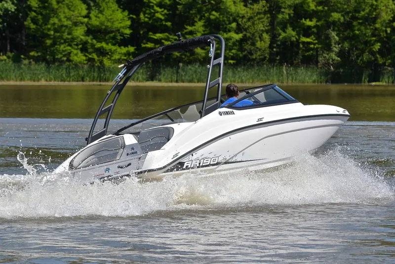 Slide: The Image of 2023 Yamaha AR190 boat cruising on a lake with lush green trees in the background. - 5
