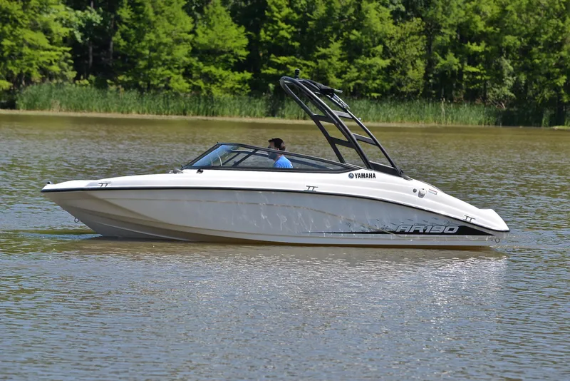 Slide: The Image of 2023 Yamaha AR190 boat cruising on a calm lake with lush green trees in the background. - 9