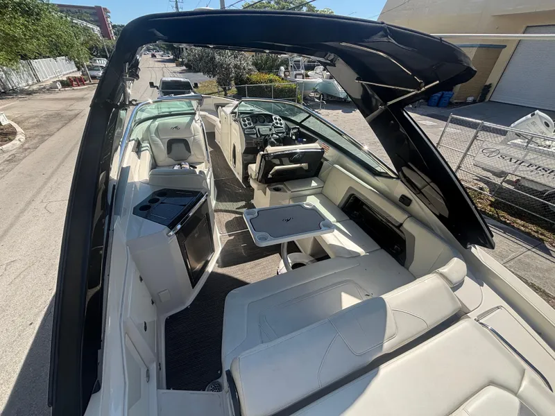 Slide: The Image of 2014 Monterey 328 Super Sport boat interior with seating and helm, docked outdoors. - 12