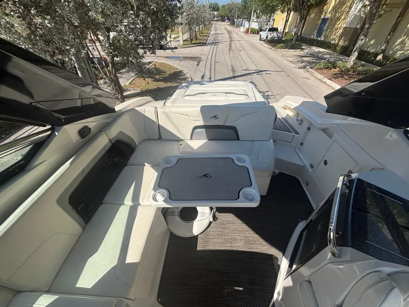 Slide: The Image of 2014 Monterey 328 Super Sport boat interior with seating and table, parked on a street. - 14
