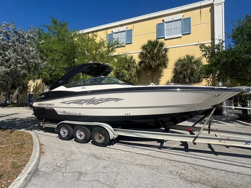 Slide: The Image of 2014 Monterey 328 Super Sport boat on trailer, parked near a yellow building. - 22