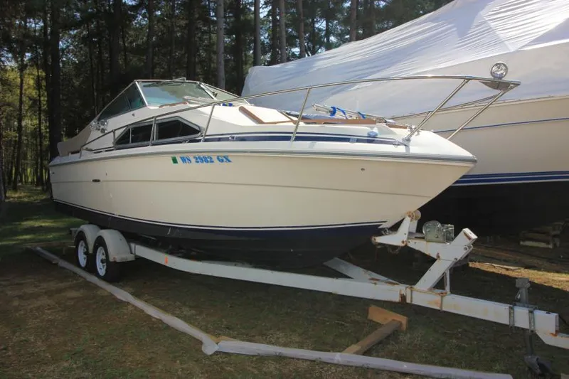 Slide: The Image of 1981 Sea Ray 245 SRV boat on trailer, parked outdoors near trees. - 1