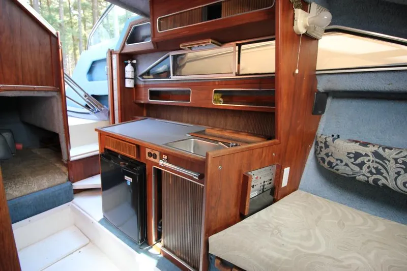 Slide: The Image of 1981 Sea Ray 245 SRV cabin interior with kitchenette, wood finish, and seating area. - 15