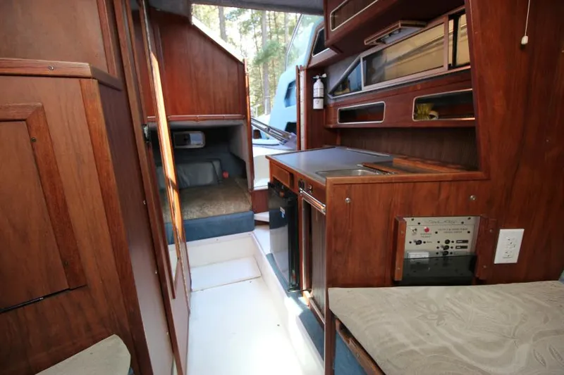 Slide: The Image of 1981 Sea Ray 245 SRV cabin interior with wood paneling and compact kitchen area. - 16