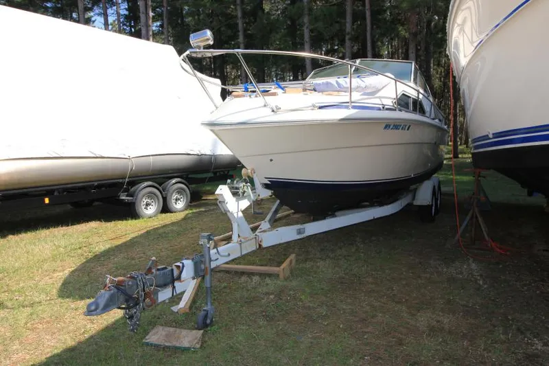 Slide: The Image of 1981 Sea Ray 245 SRV boat on trailer, parked outdoors in wooded area. - 2