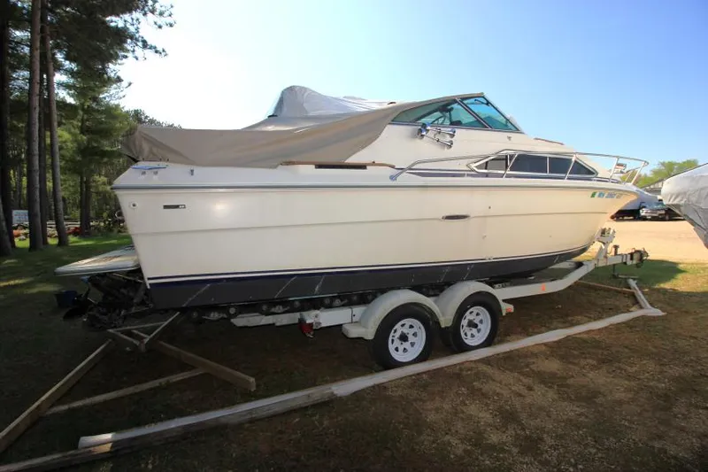 Slide: The Image of 1981 Sea Ray 245 SRV boat on trailer, parked outdoors under clear sky. - 5