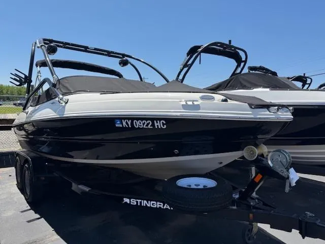 Slide: The Image of 2016 Stingray 208LR boat on trailer, black and white, parked outdoors. - 1