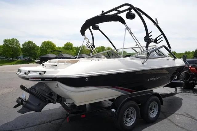 Slide: The Image of 2016 Stingray 208LR boat on trailer, parked outdoors with trees in background. - 4