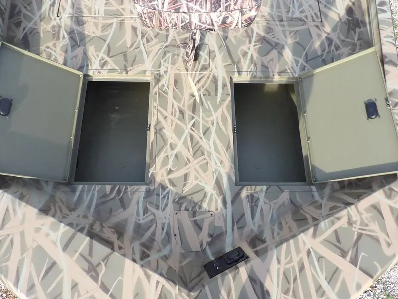 Slide: The Image of 2025 Crestliner 2070 Retriever SCHD boat with open storage compartments, camo pattern. - 25