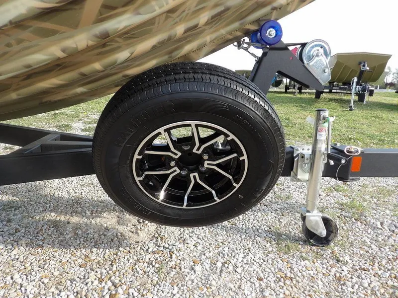 Slide: The Image of 2025 Crestliner 2070 Retriever SCHD trailer wheel on gravel, showcasing sturdy design. - 34