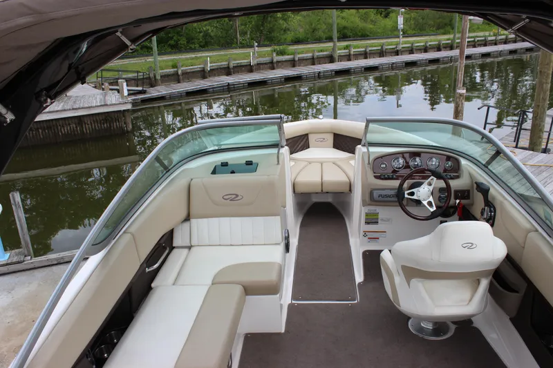 Slide: The Image of 2012 Regal 2100 RS Bowrider interior with seating and steering wheel, docked by a calm river. - 11