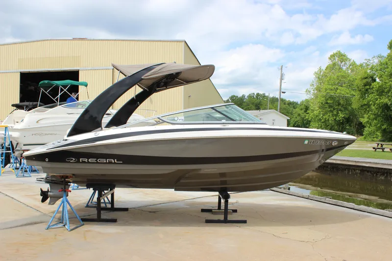 Slide: The Image of 2012 Regal 2100 RS Bowrider boat on stands near a warehouse and trees. - 7