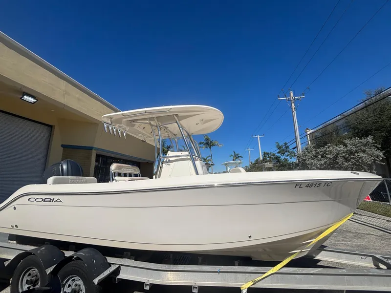Slide: The Image of 2022 Cobia 237 Center Console boat on trailer, parked outdoors under clear blue sky. - 0
