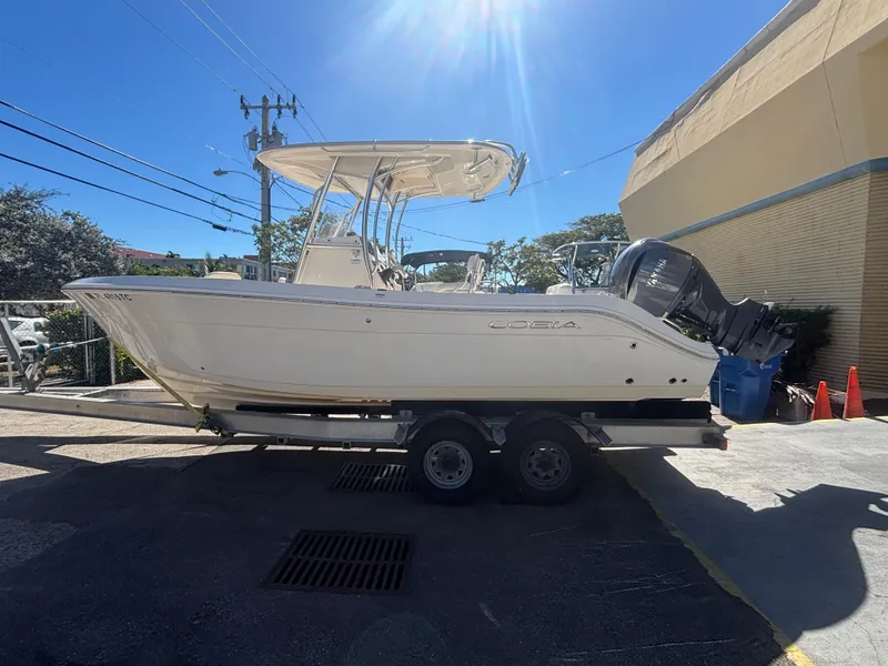 Slide: The Image of 2022 Cobia 237 Center Console boat on trailer, parked outdoors under clear blue sky. - 17