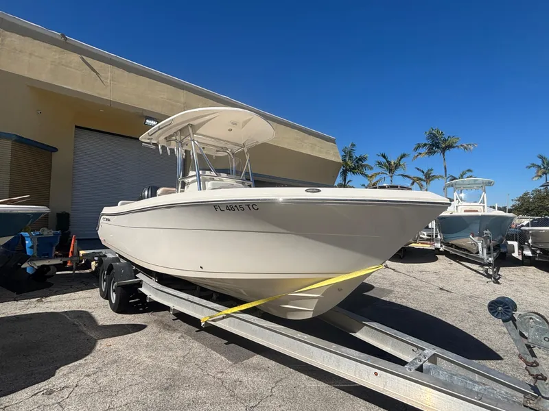 Slide: The Image of 2022 Cobia 237 Center Console boat on trailer, parked outdoors under clear blue sky. - 2