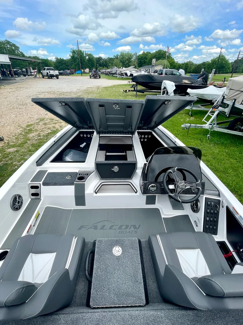 Slide: The Image of 2025 Falcon F205 boat interior with open storage compartments, steering wheel, and seating under a blue sky. - 3