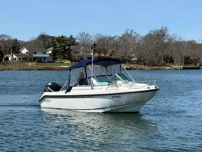 Slide: The Image of 2005 Boston Whaler 210 Ventura boat cruising on a calm lake near shoreline homes. - 2