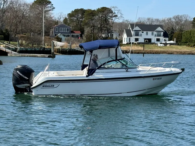 Slide: The Image of 2005 Boston Whaler 210 Ventura boat on calm water near residential shoreline. - 3
