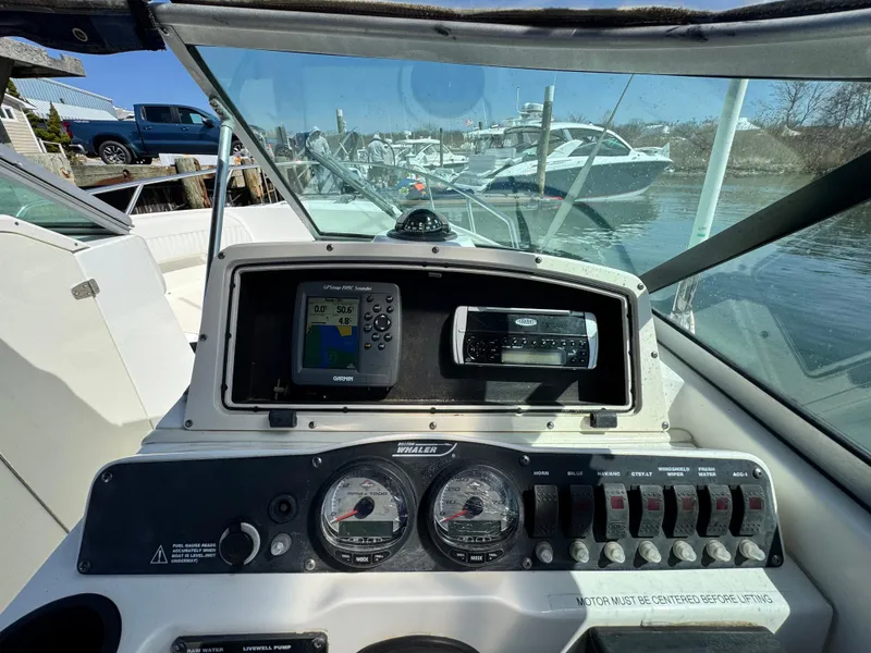 Slide: The Image of 2005 Boston Whaler 210 Ventura dashboard with navigation and control instruments, docked near other boats. - 7