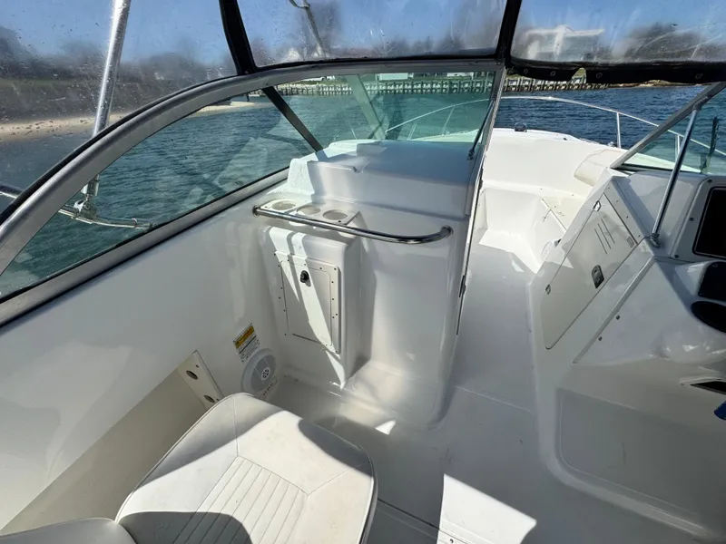 Slide: The Image of 2005 Boston Whaler 210 Ventura boat interior with seating and console, on calm water. - 9