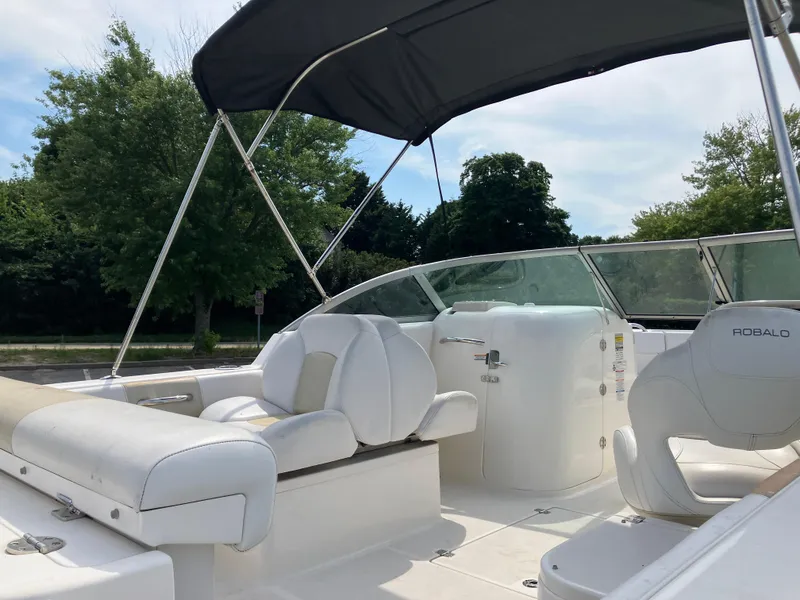 Slide: The Image of 2016 Robalo R227 Dual Console boat with white seating and canopy, set against a lush green backdrop. - 26