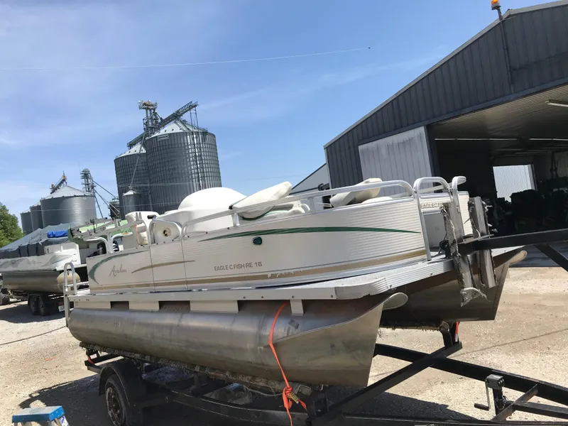 Slide: The Image of 2009 Avalon Eagle 16' pontoon boat on trailer near industrial buildings. - 2